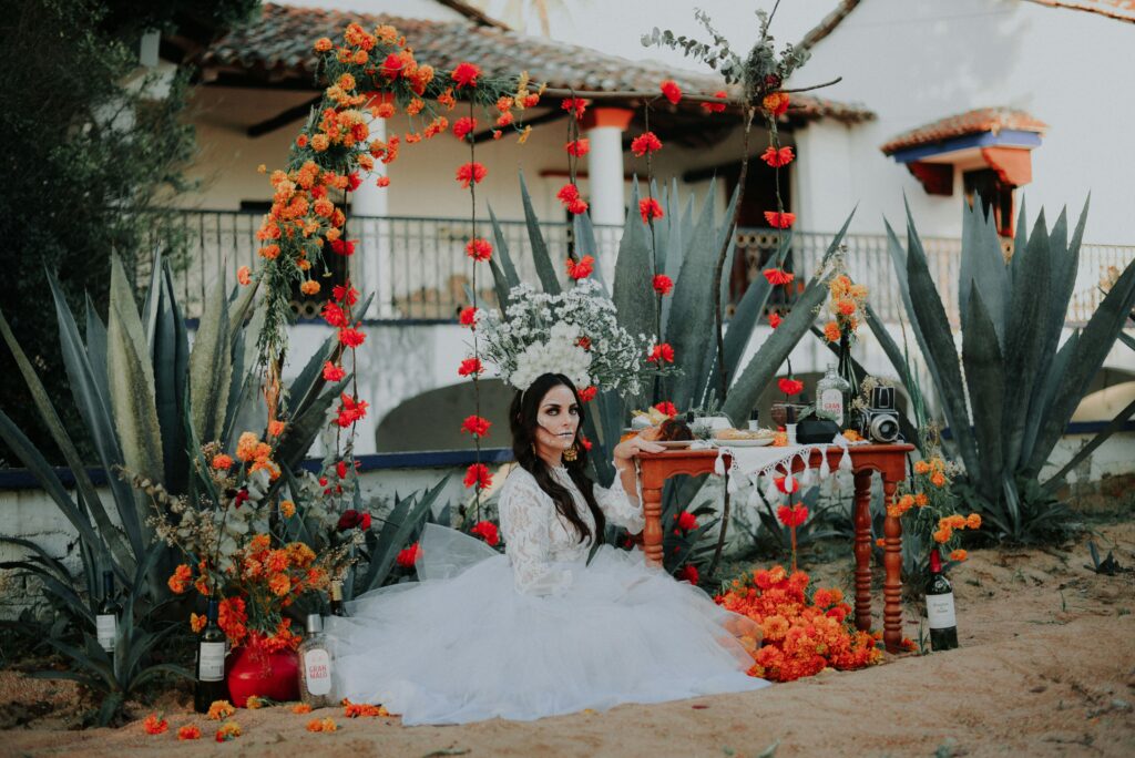 pexels-photo-10028993-10028993 Stunning Day of the Dead themed bride surrounded by vibrant flowers outdoors.
